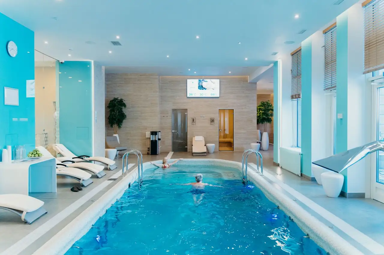 Luxurious indoor swimming pool in a modern spa with lounge chairs and soft lighting